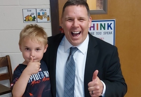 Dr. Benyon is pictured posing with a kindergarten student as both give  a thumbs up