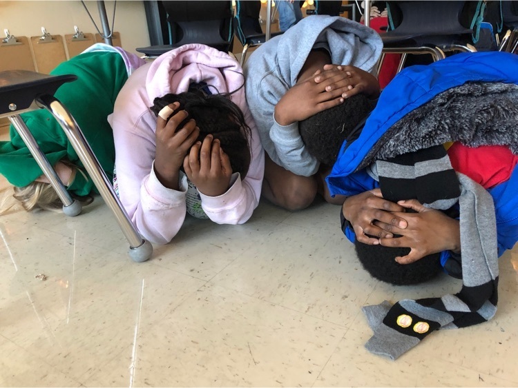 students perform an earthquake drill and are under their desks 