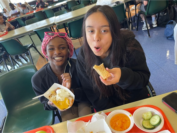 two girls enjoy crispitos in the cafeteria 