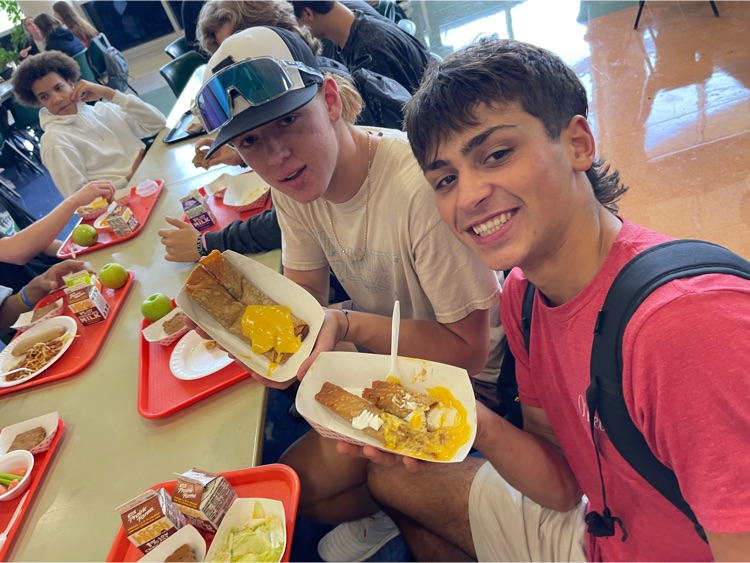 two boys smile as they hold their lunches