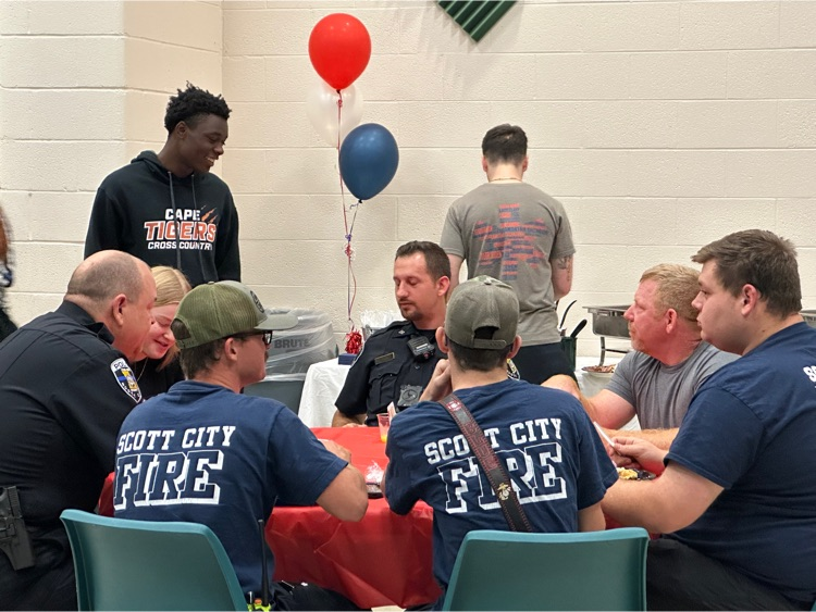 a high school student welcomes a table of fire fighters for a breakfast