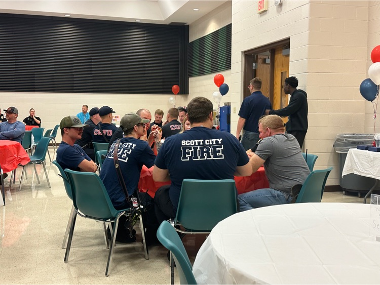 a group of first responders are seated at tables to eat breakfast
